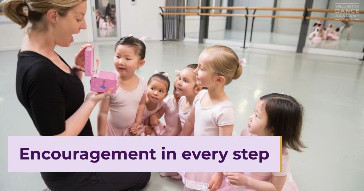 Ballet teacher showing reward to smiling young girls in pink dancewear.