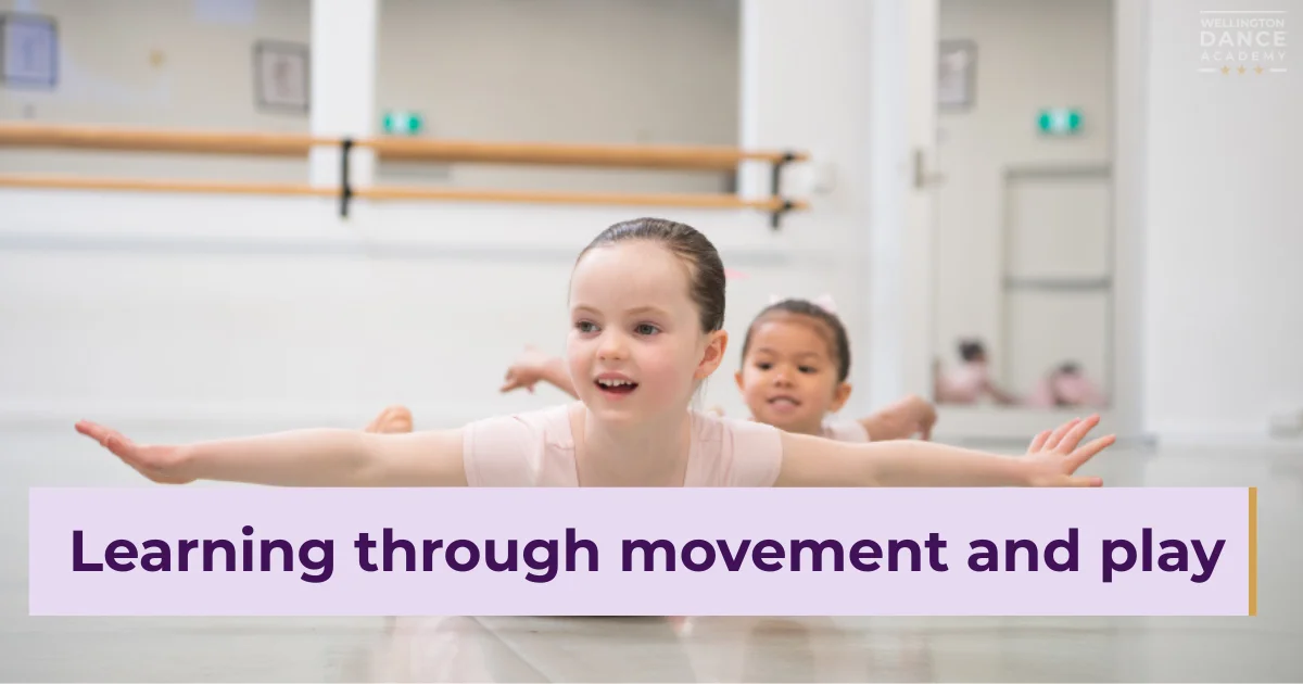 Teacher guiding young ballerinas lined up in pink tutus.